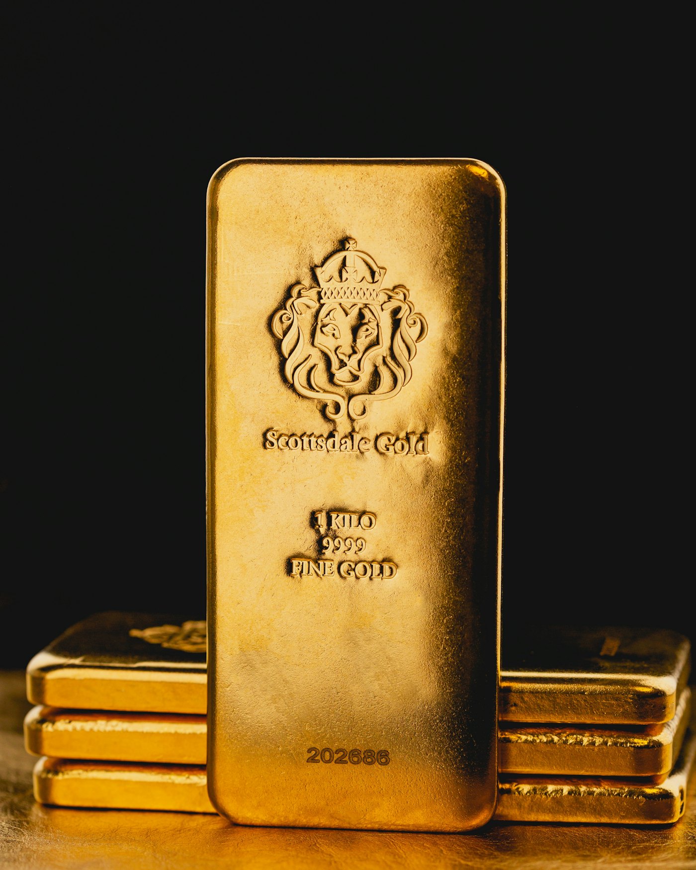 A one kilo fine gold bar standing in front of stacked bars