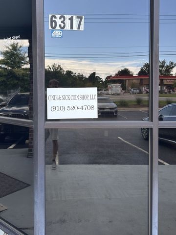 The entrance at 6317 with the Cindi and Nick Coin Shop, LLC sign in the window and opening hours on the door