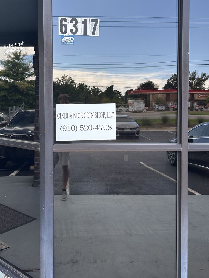 The entrance at 6317 with the Cindi and Nick Coin Shop, LLC sign in the window and opening hours on the door